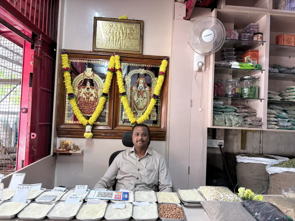 Nagendra Prasad at the counter of Sri RK Traders, a wholesale grocery store in Bangalore, displaying rice and grains.